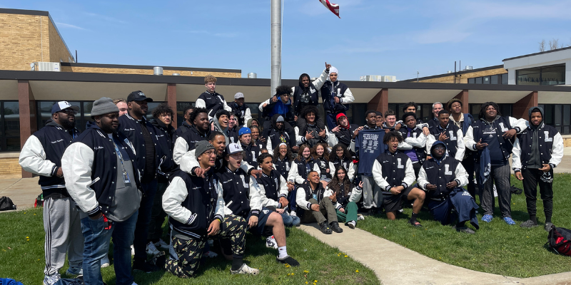 Varsity Football and Cheerleaders pose in front of Lackawanna Middle and High School