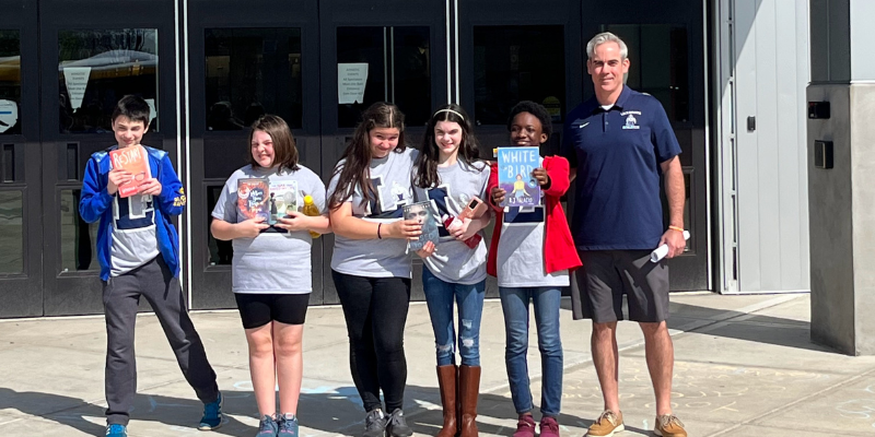 Mr. Conrad and Lackawanna Middle School Students pose for a photo while holding books.